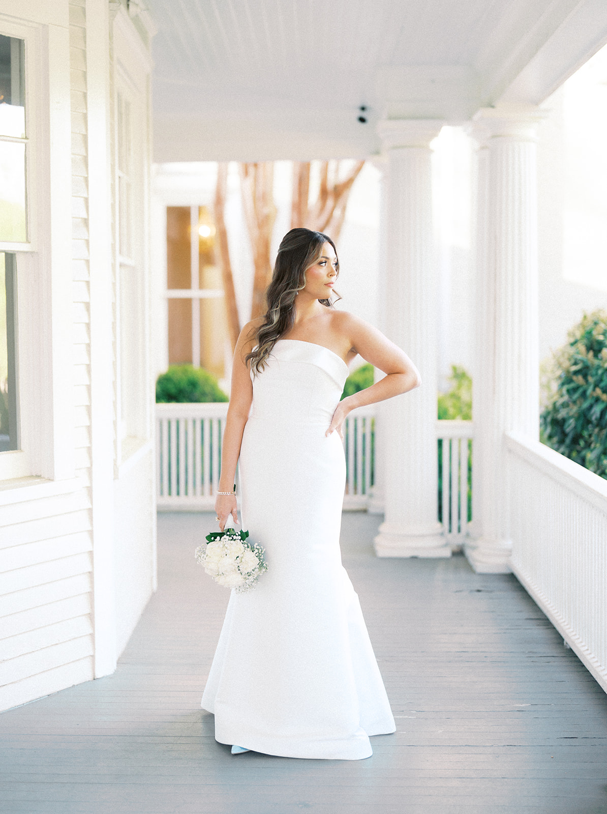 Bride posing on the front porch of the reception space of McAlister-Leftwich in Greensboro